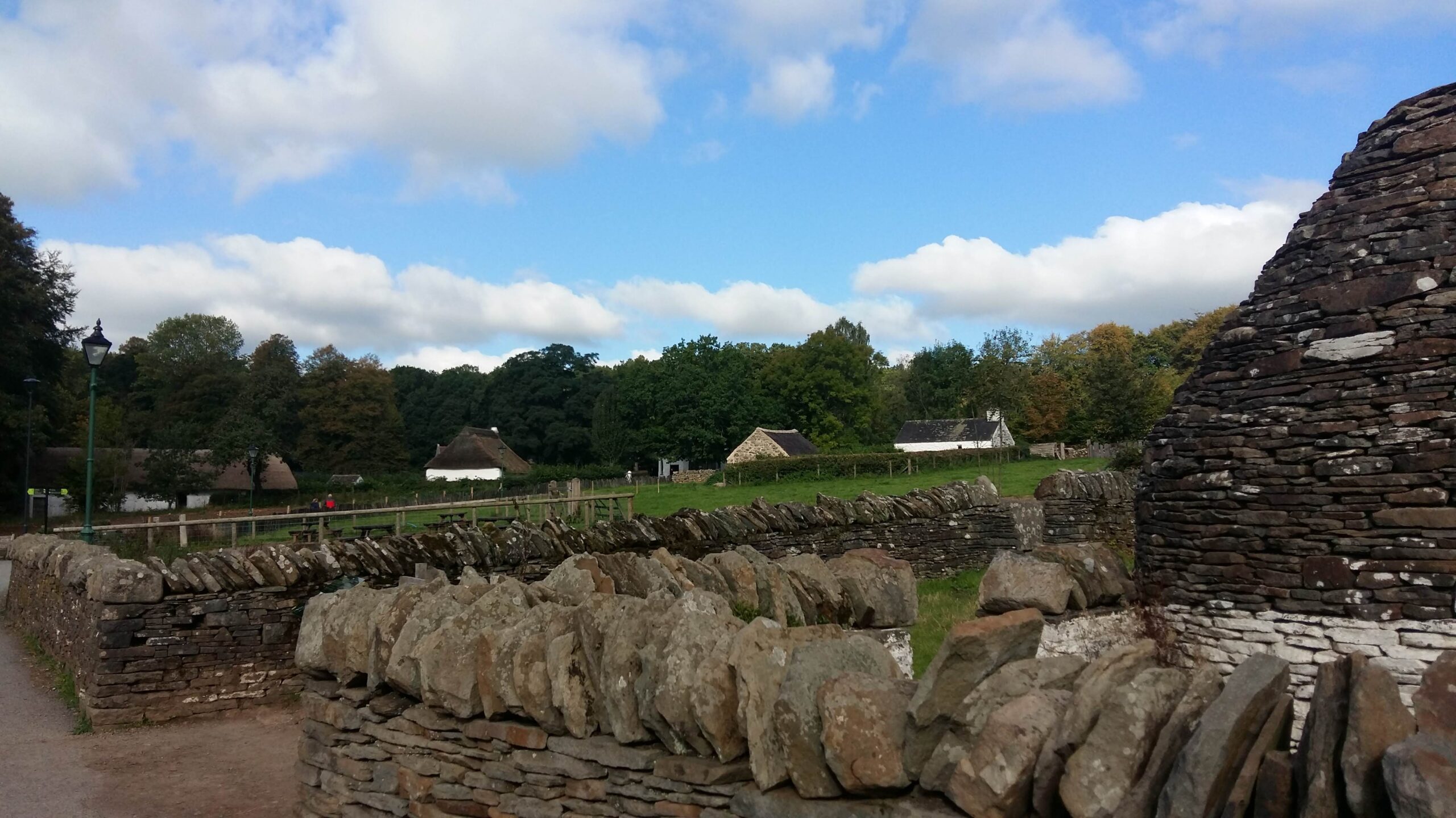 Outdoor view of the St Fagans museum including historic buildings, green gardens and stone fences