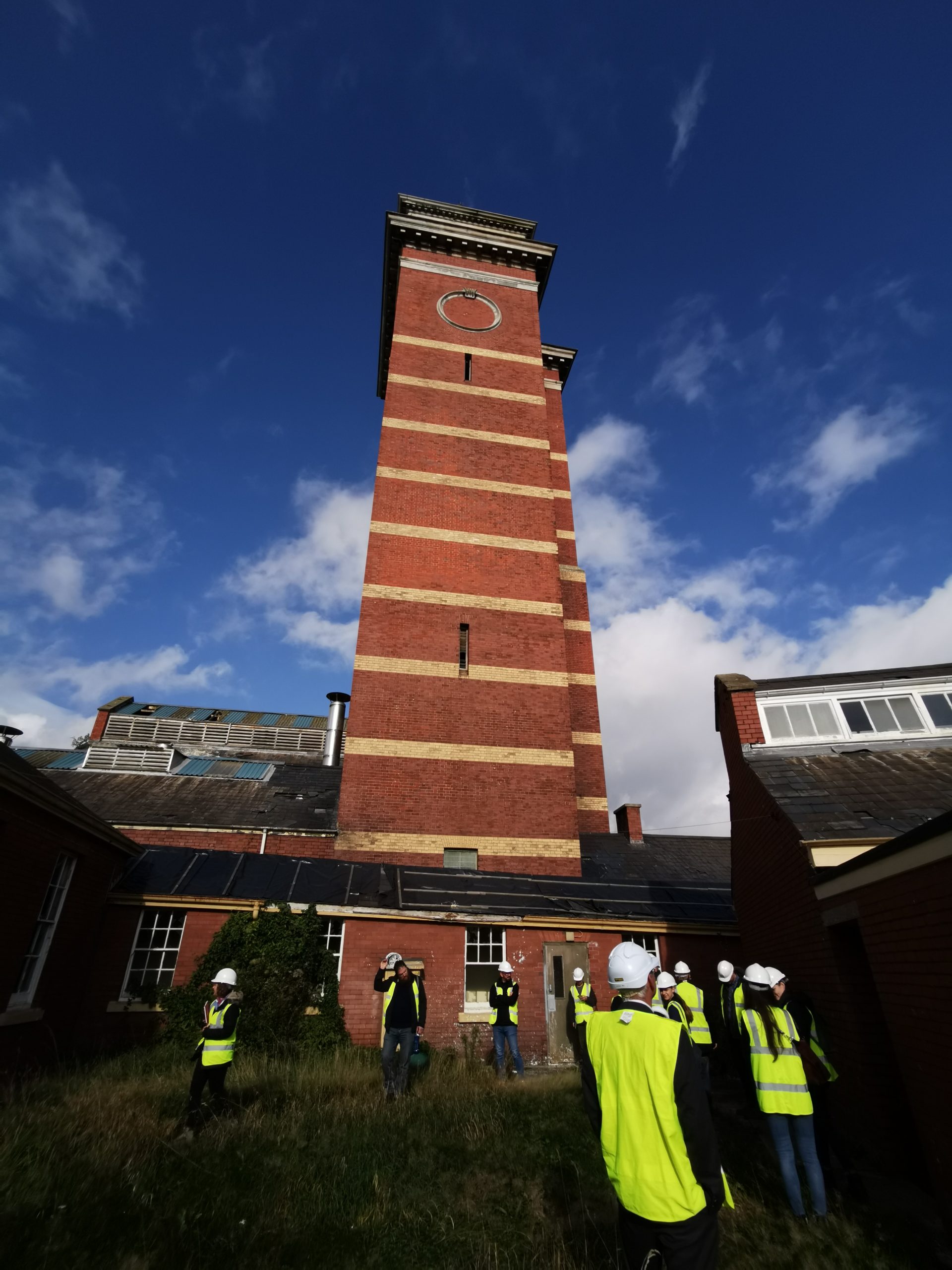 Students in PPE at base of Whitchurch Hospital red brick water tower